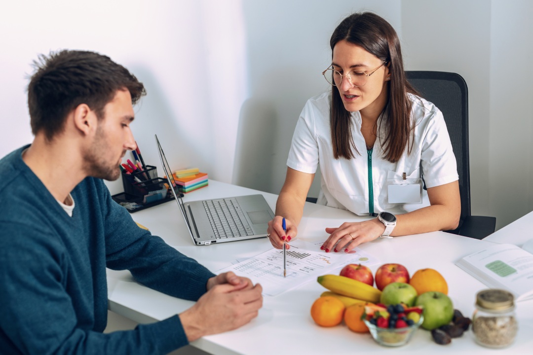 Shot of beautiful young nutritionist woman explaining to her patient the diet he should follow to lose weight in the consultation.