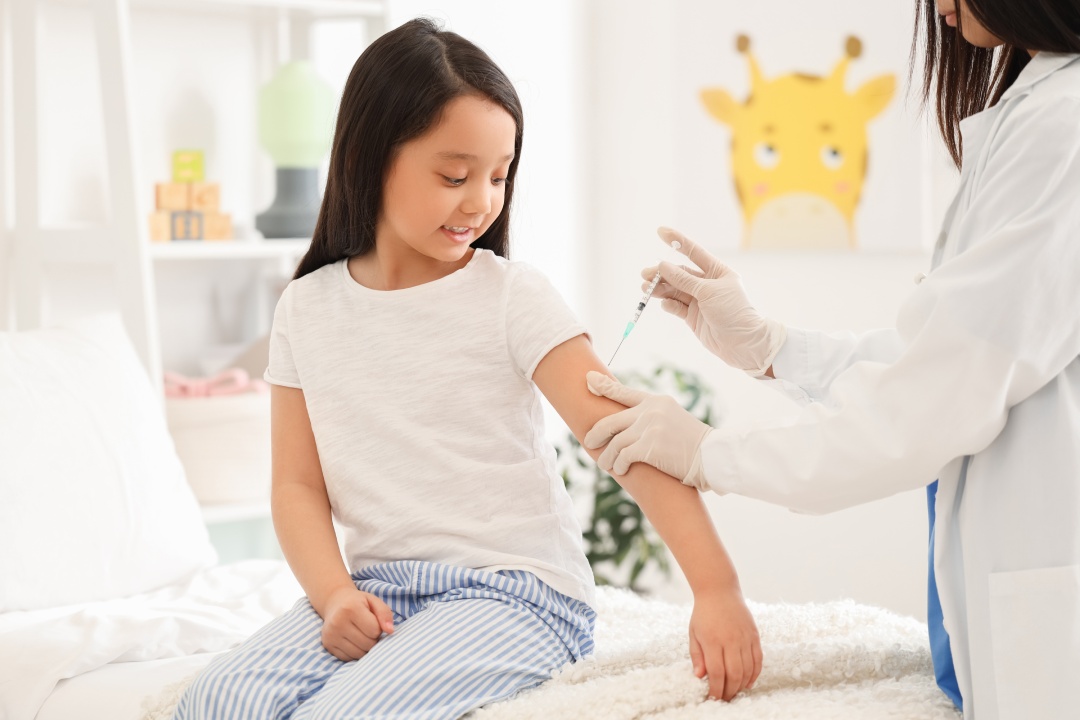 Little Asian girl receiving vaccine at hospital