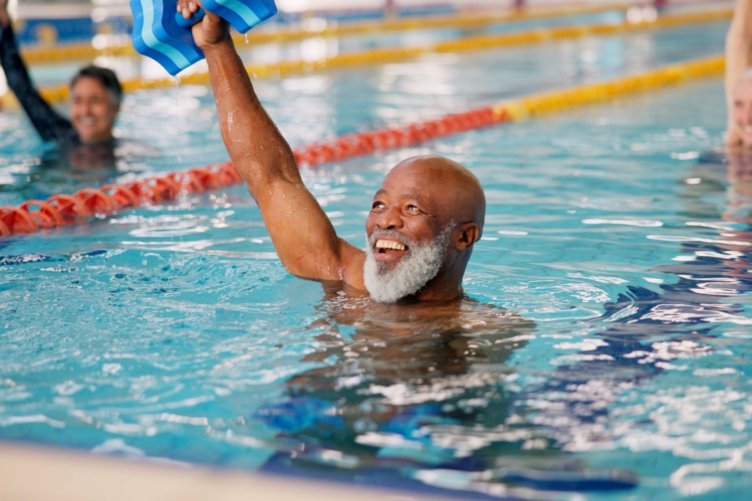 Mancuerna, entrenamiento y hombre maduro en piscina para ejercicio, cuerpo sano y músculo fuerte. Clase de pesas, agua y aeróbic para fitness, fisioterapia y rehabilitación de personas mayores felices.