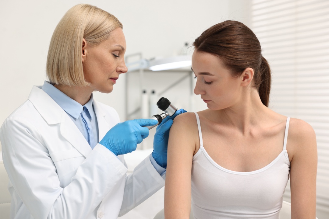 Dermatologist with dermatoscope examining patient in clinic