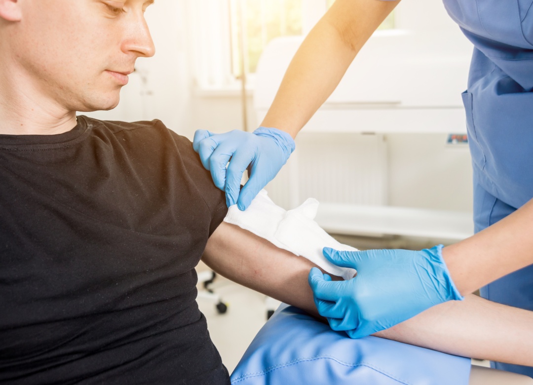 Enfermera vendando la mano de un paciente con quemaduras. Historial médico